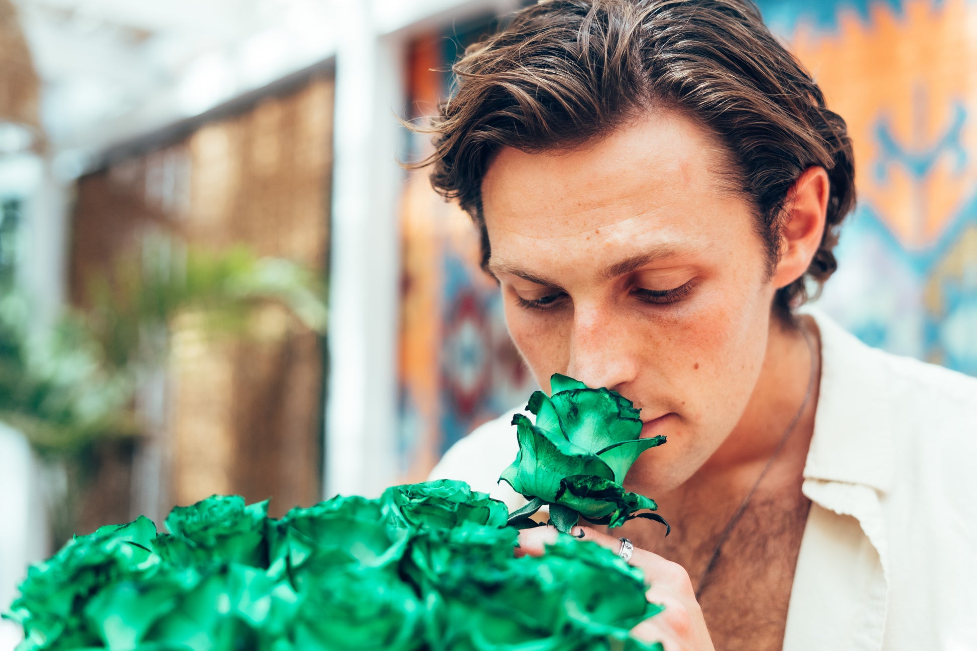 Man smelling a green rose in an outdoor setting