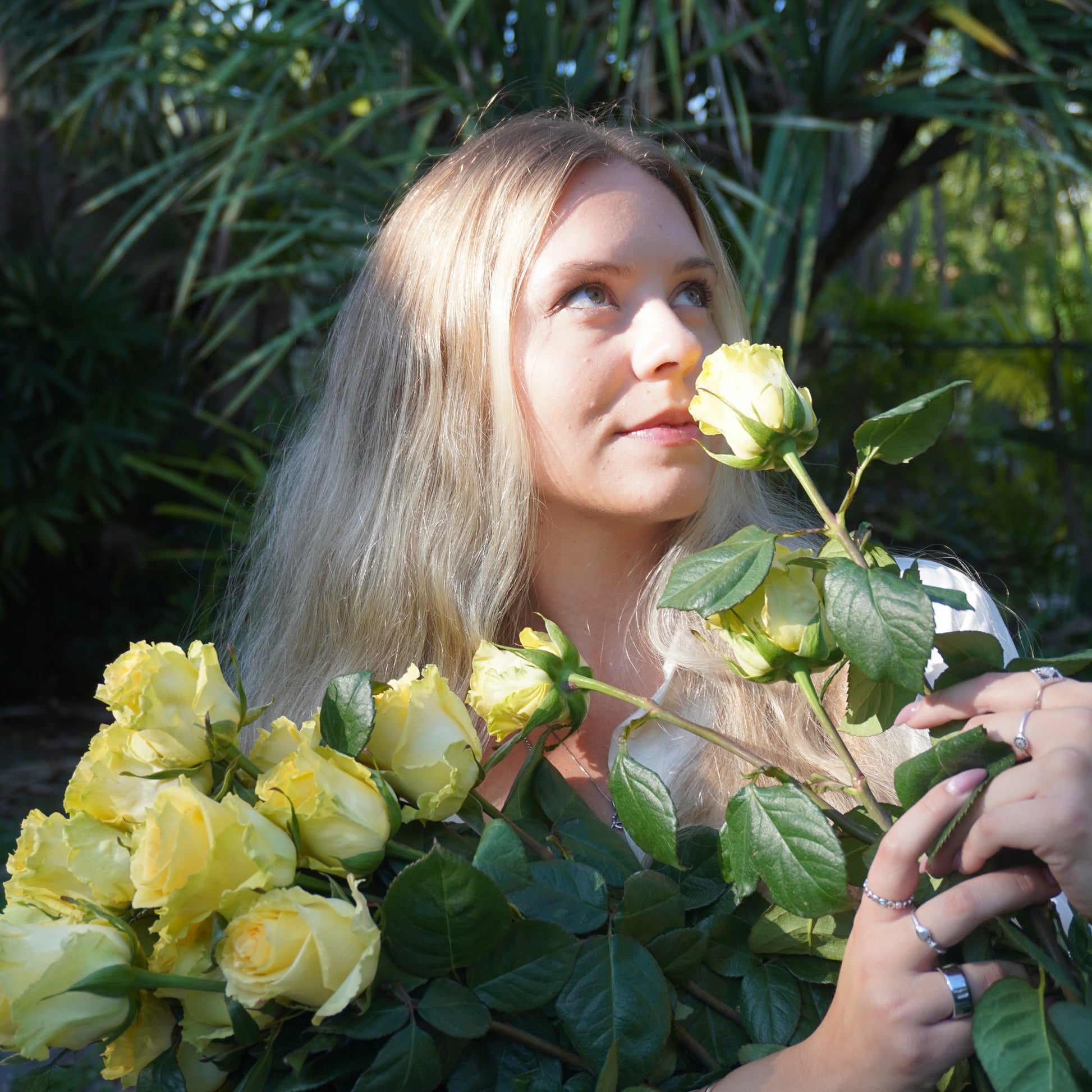 Woman holding yellow roses surrounded by greenery