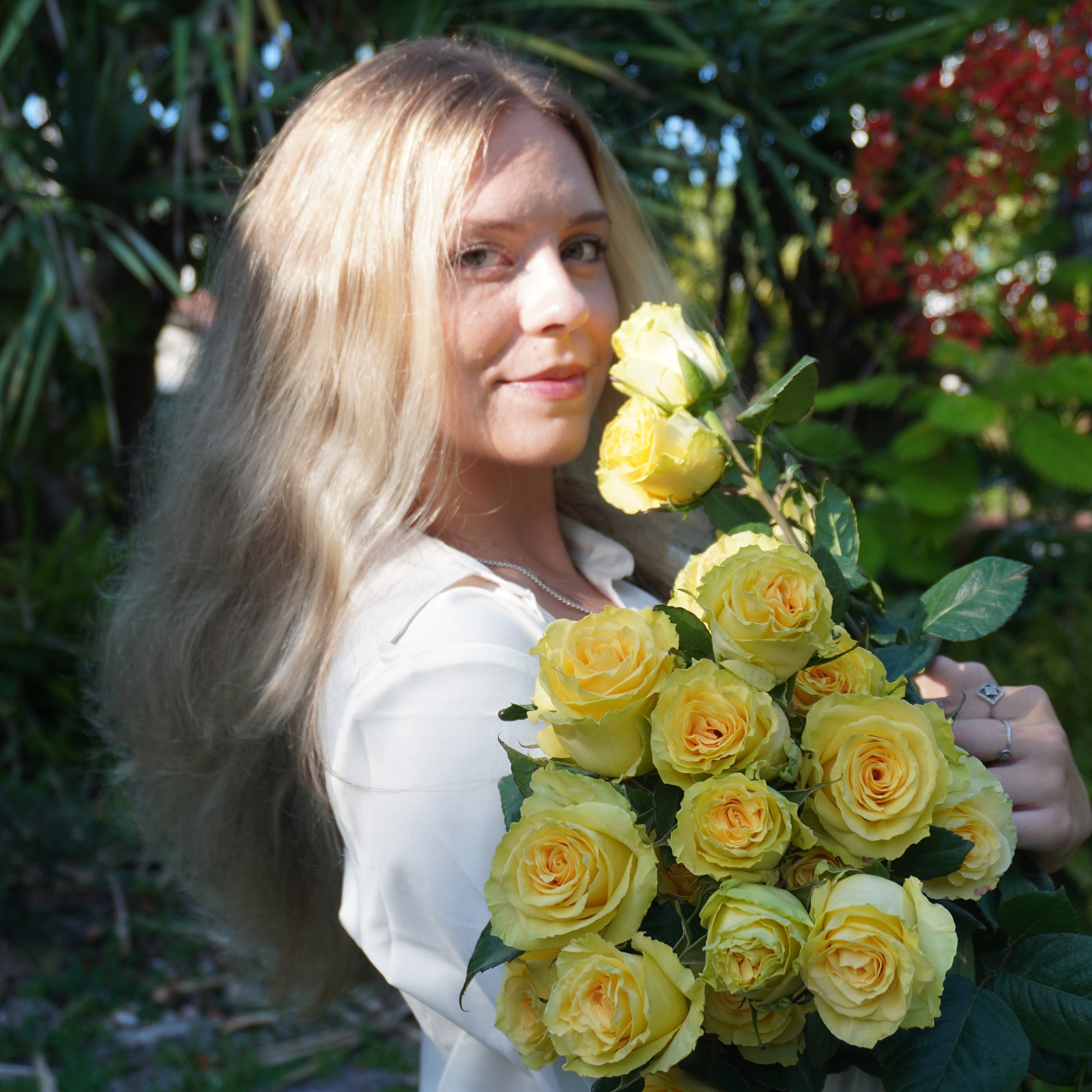 Woman holding a bouquet of yellow roses in a natural setting