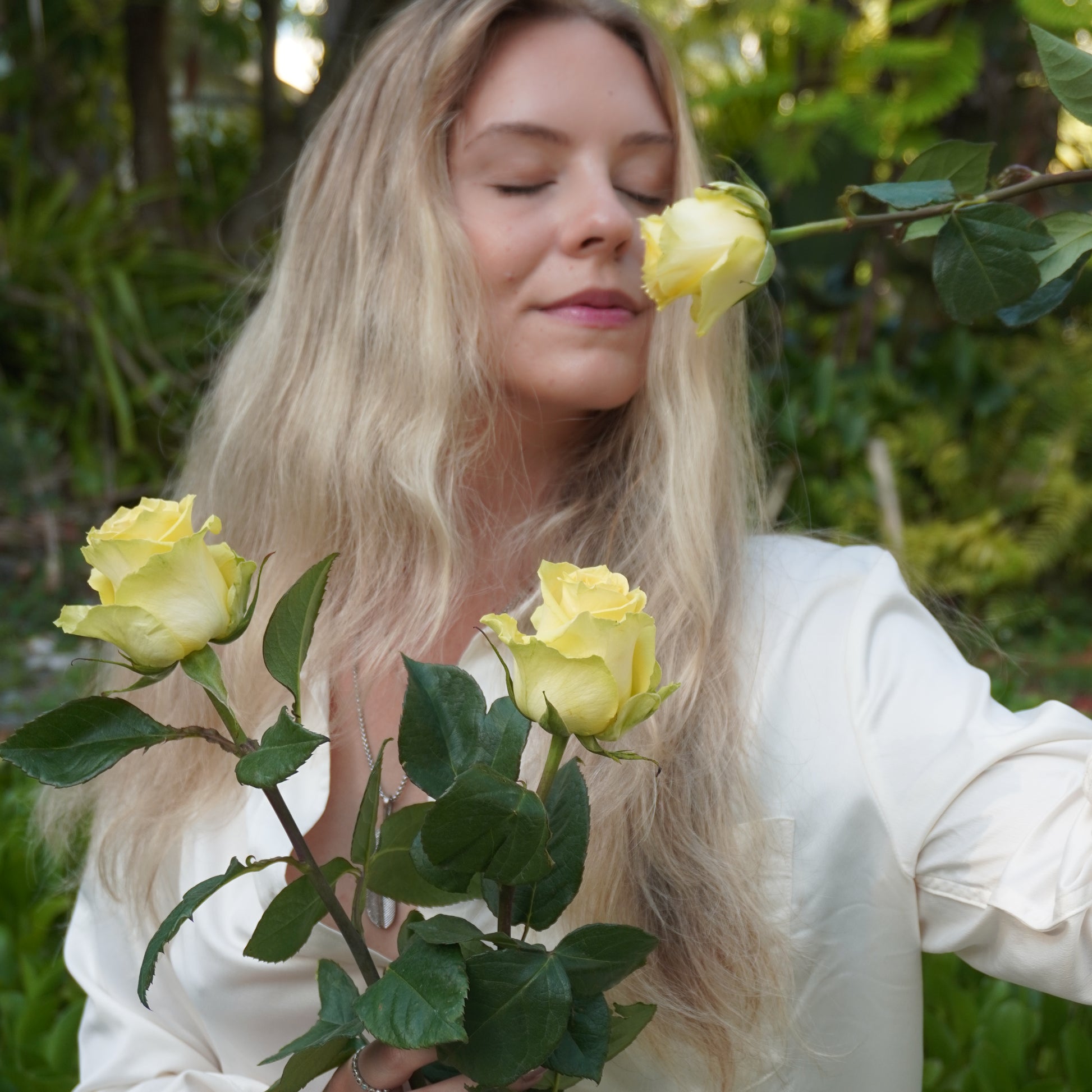 Woman smelling with yellow roses in a natural setting