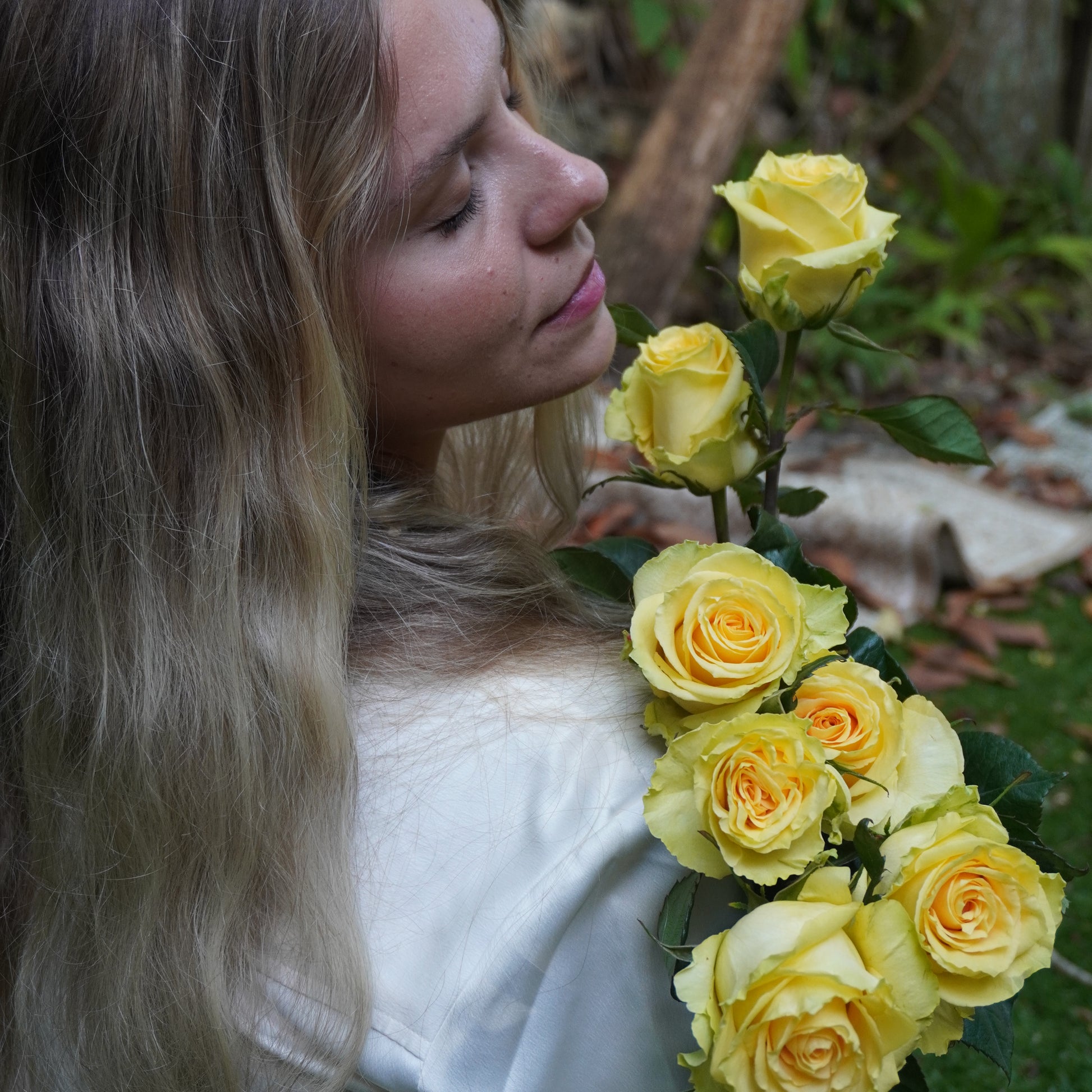 Woman lying on grass with yellow roses in a natural setting