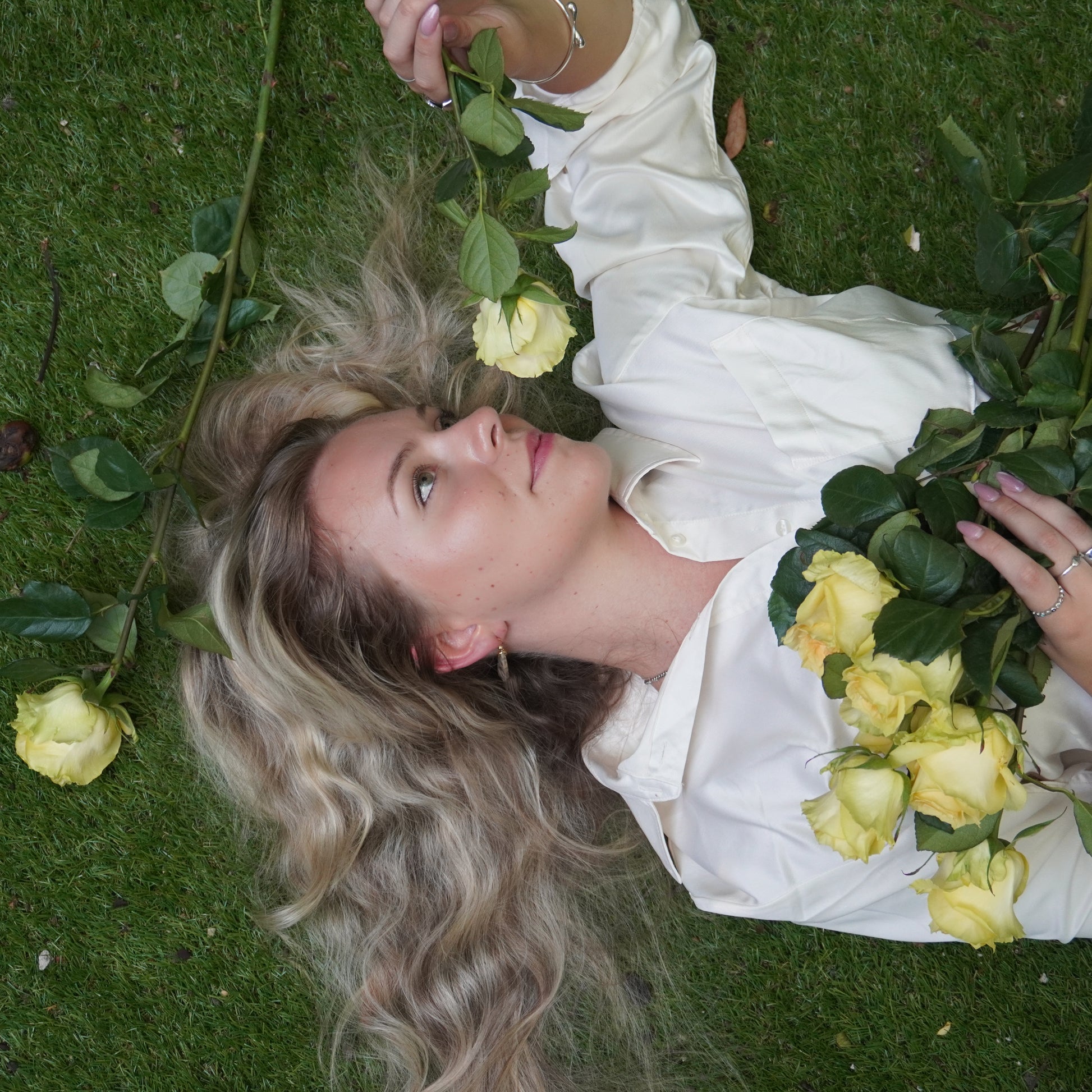 Woman lying on grass with yellow roses