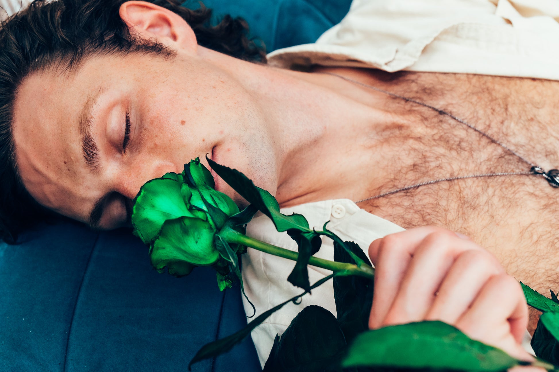 Person lying down holding green roses with a blurred background