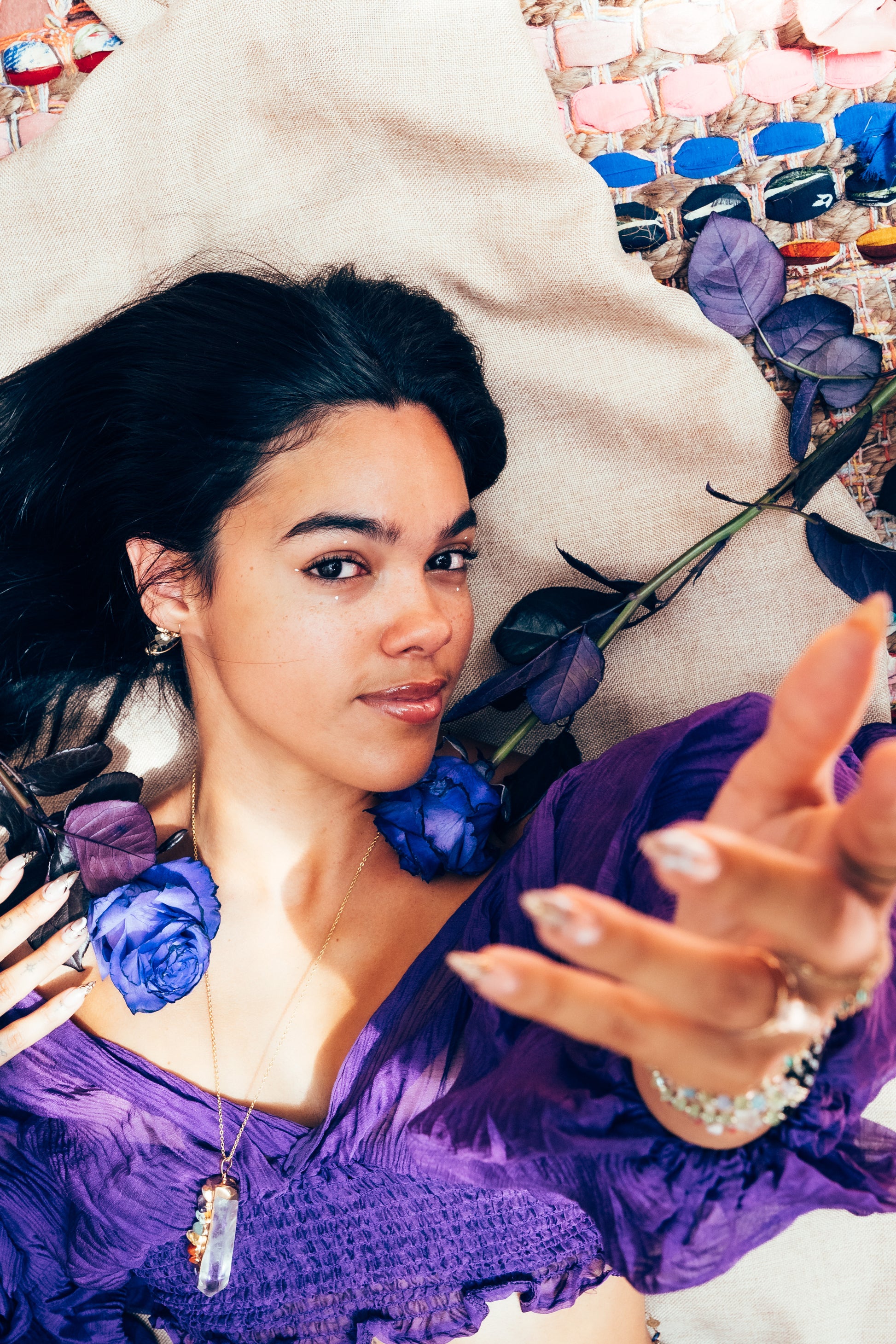 Woman in a purple dress surrounded by flowers and jewelry