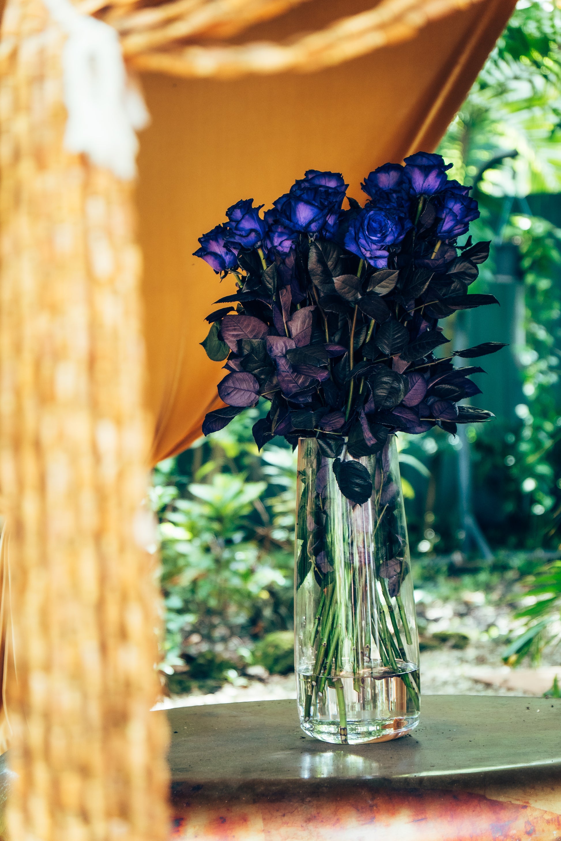 Bouquet of purple flowers in a clear vase on a windowsill with a blurred outdoor background