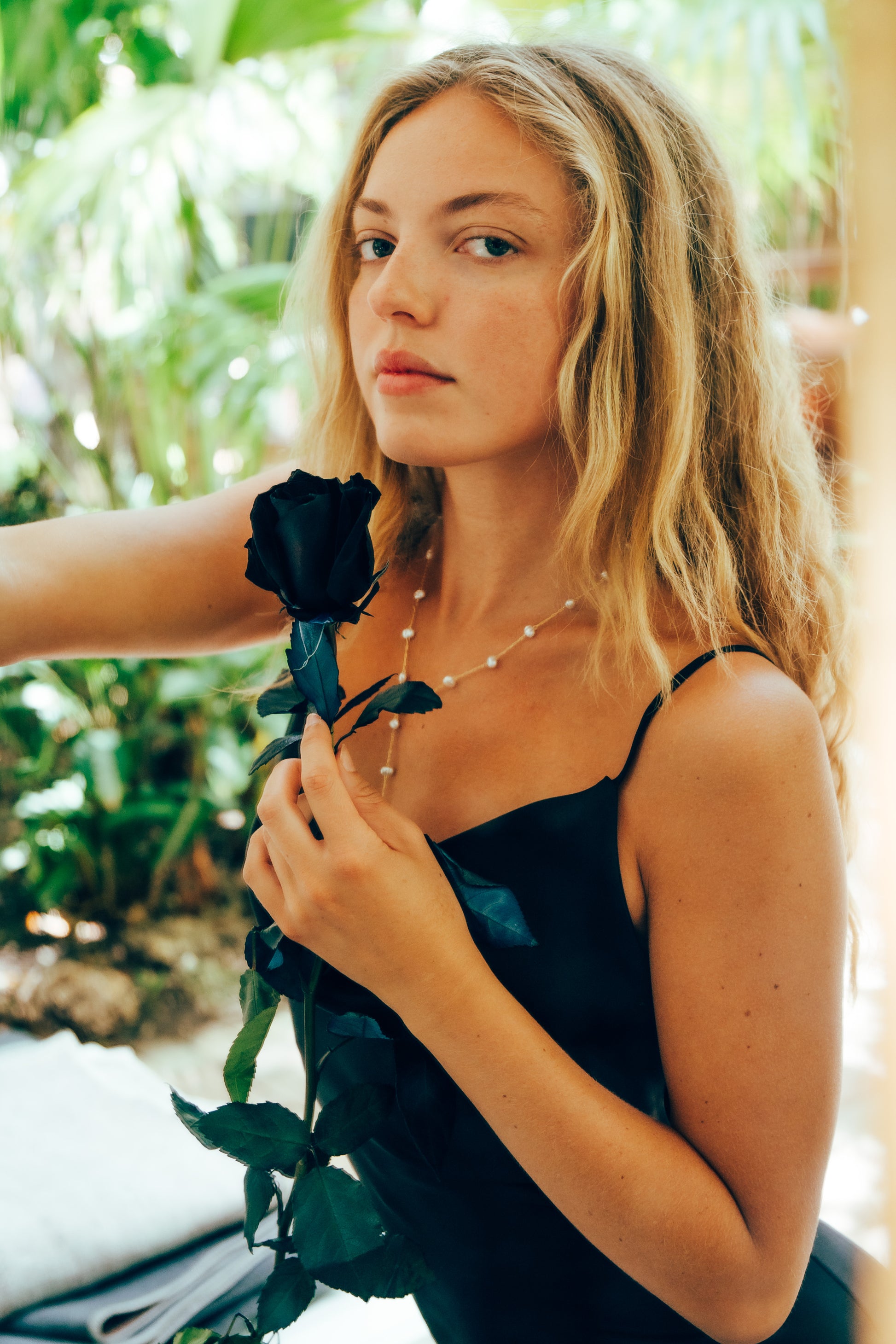 Woman holding a black rose with a blurred natural background
