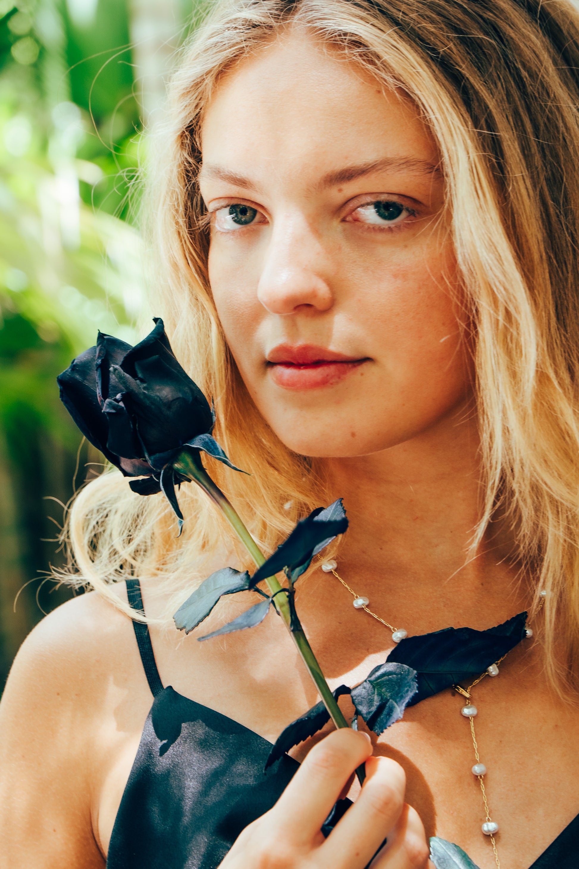 Woman holding a black rose with a blurred green background