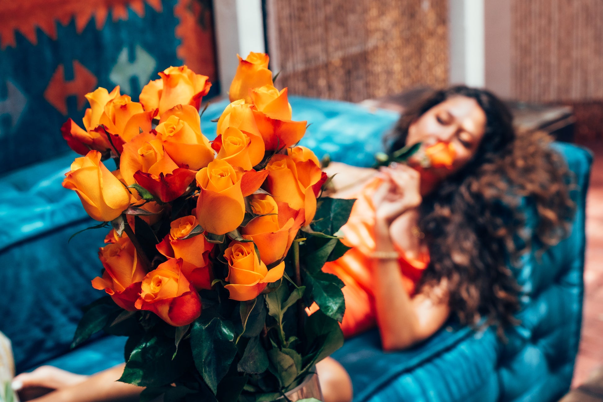 Woman lying on a couch holding a bouquet of orange flowers