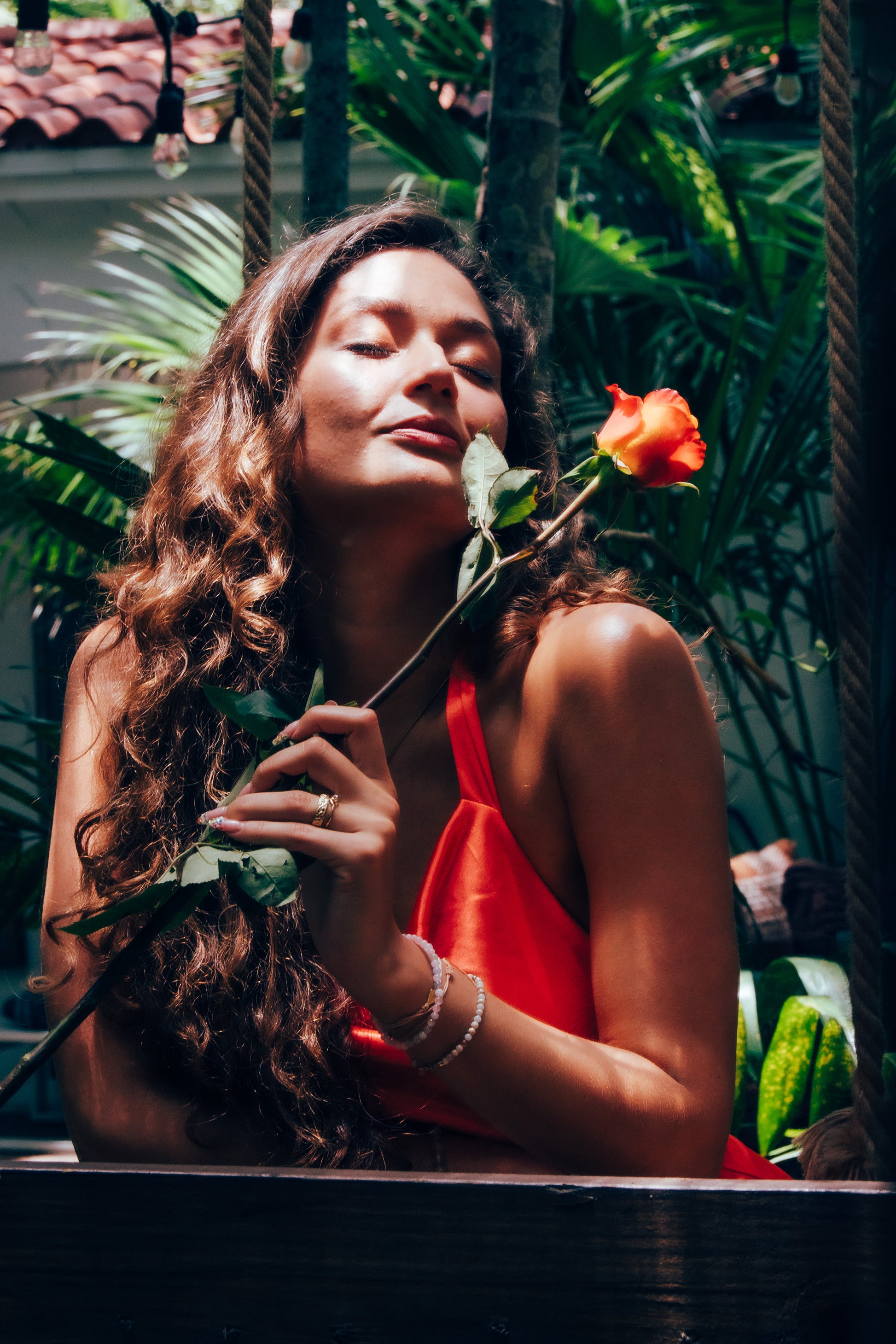 Woman holding a orange rose in a tropical setting