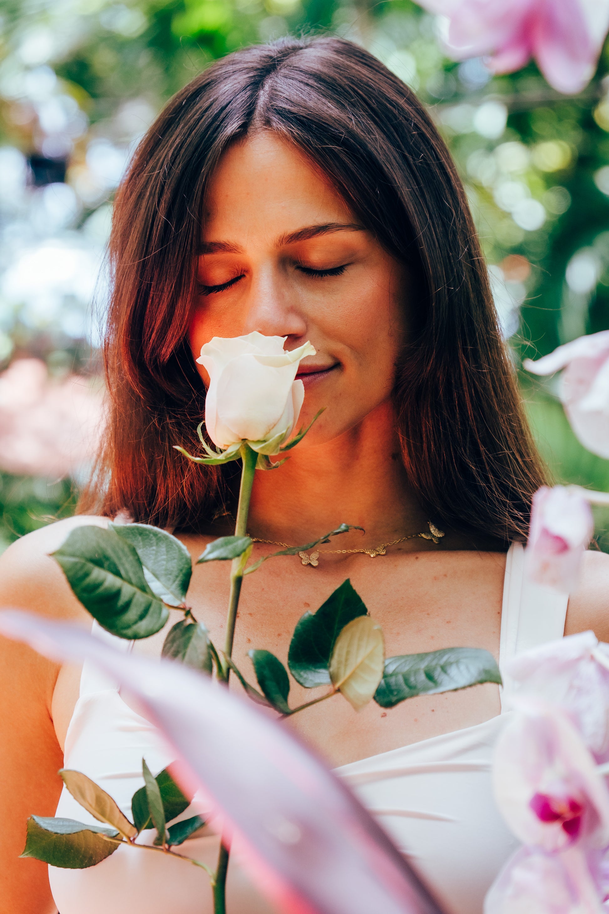 Woman smelling a pink rose with blurred floral background