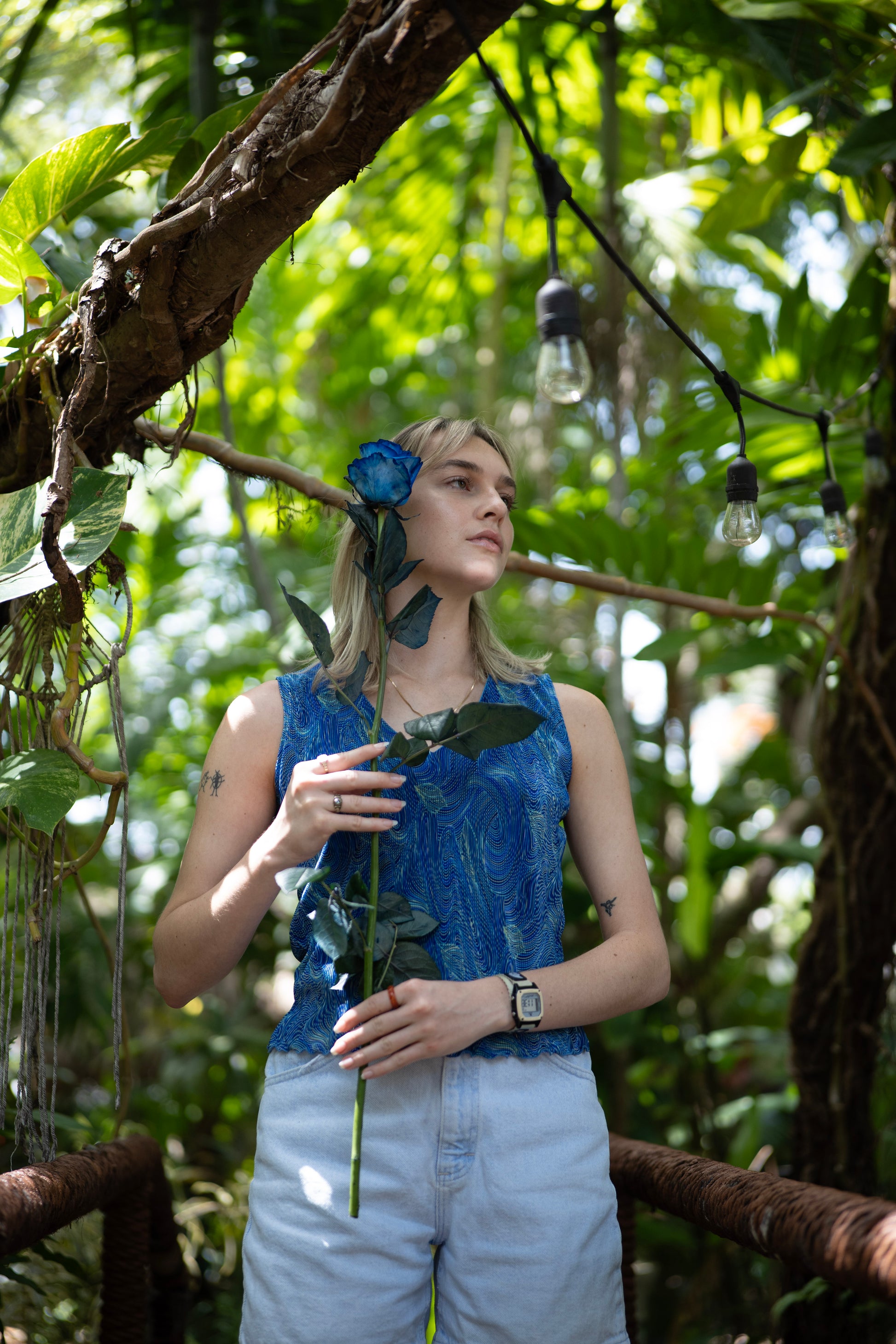 Woman holding a flower in a lush green forest setting