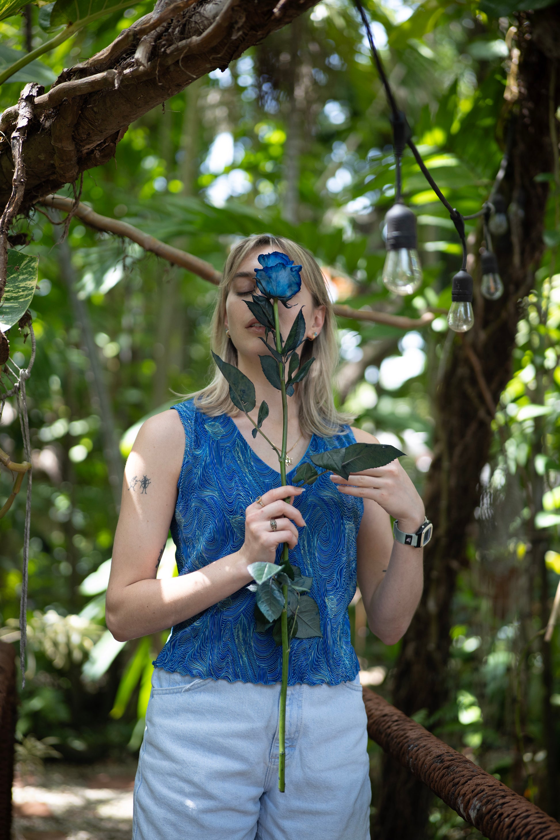 Person holding a blue flower in a forest setting