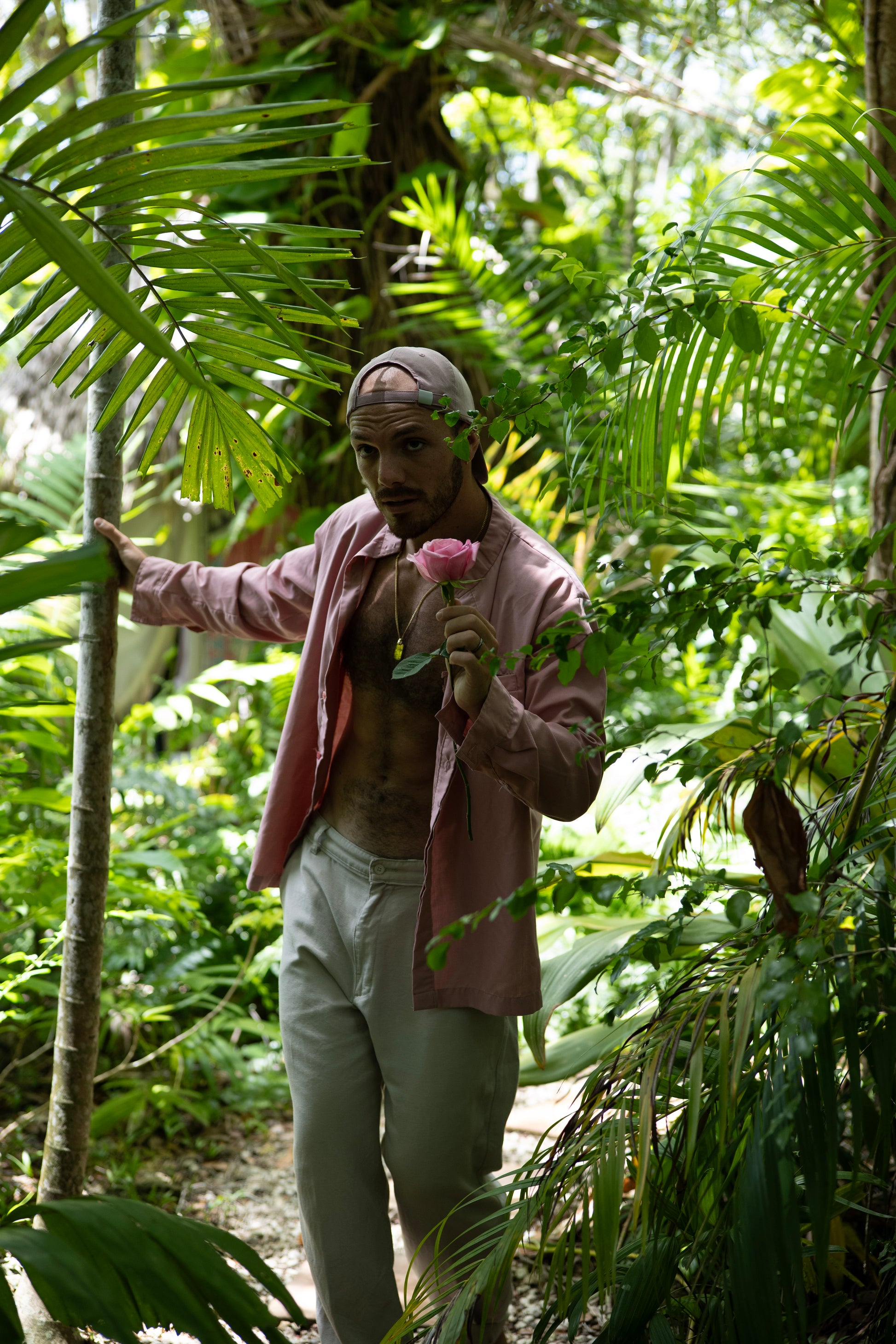 Person holding a flower in a lush green forest