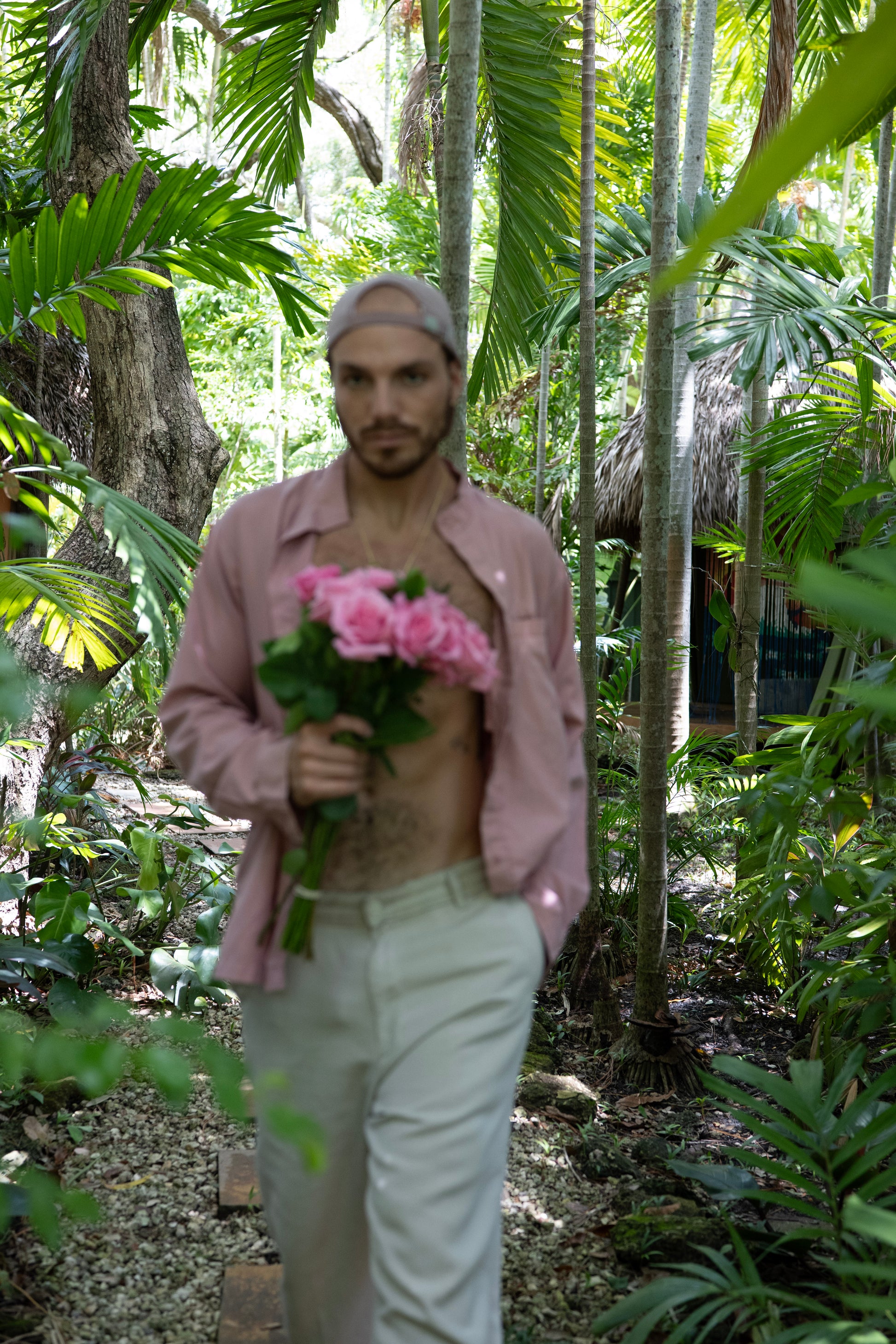 Person holding pink flowers in a tropical forest setting