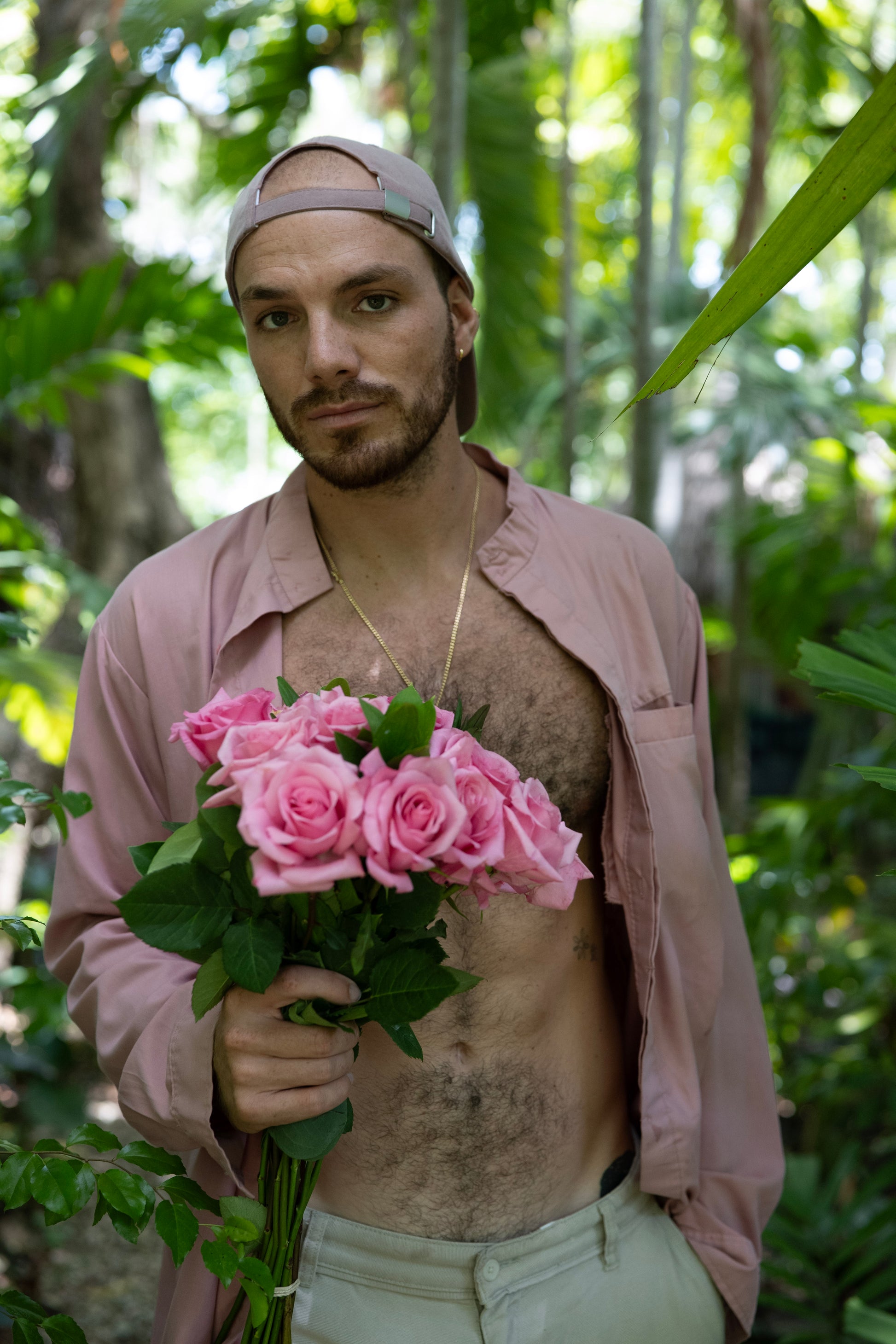 Man holding pink roses in a forest setting