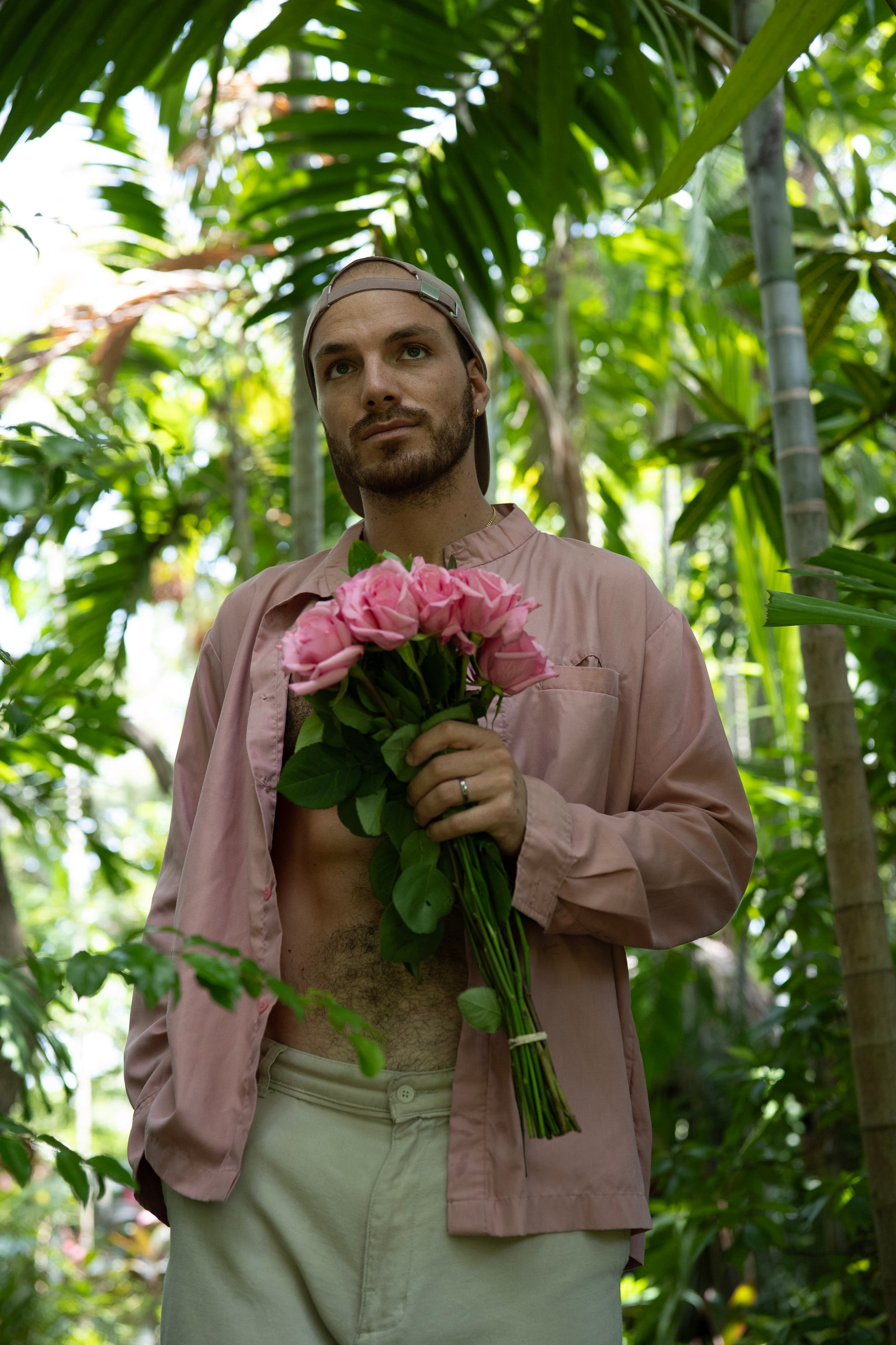 Man holding pink flowers in a tropical setting