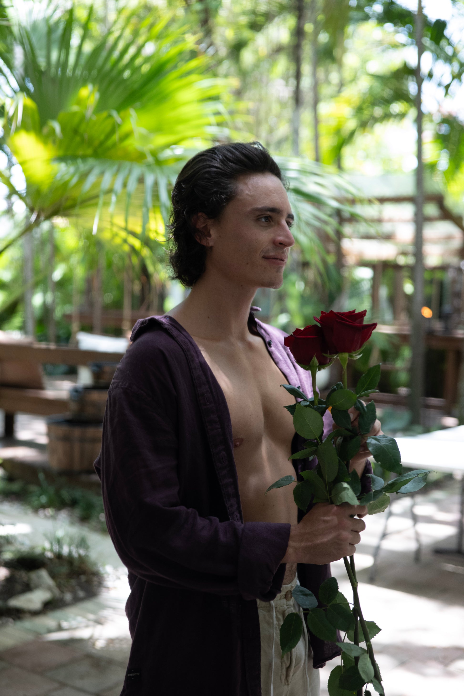 Person holding red roses in a tropical setting