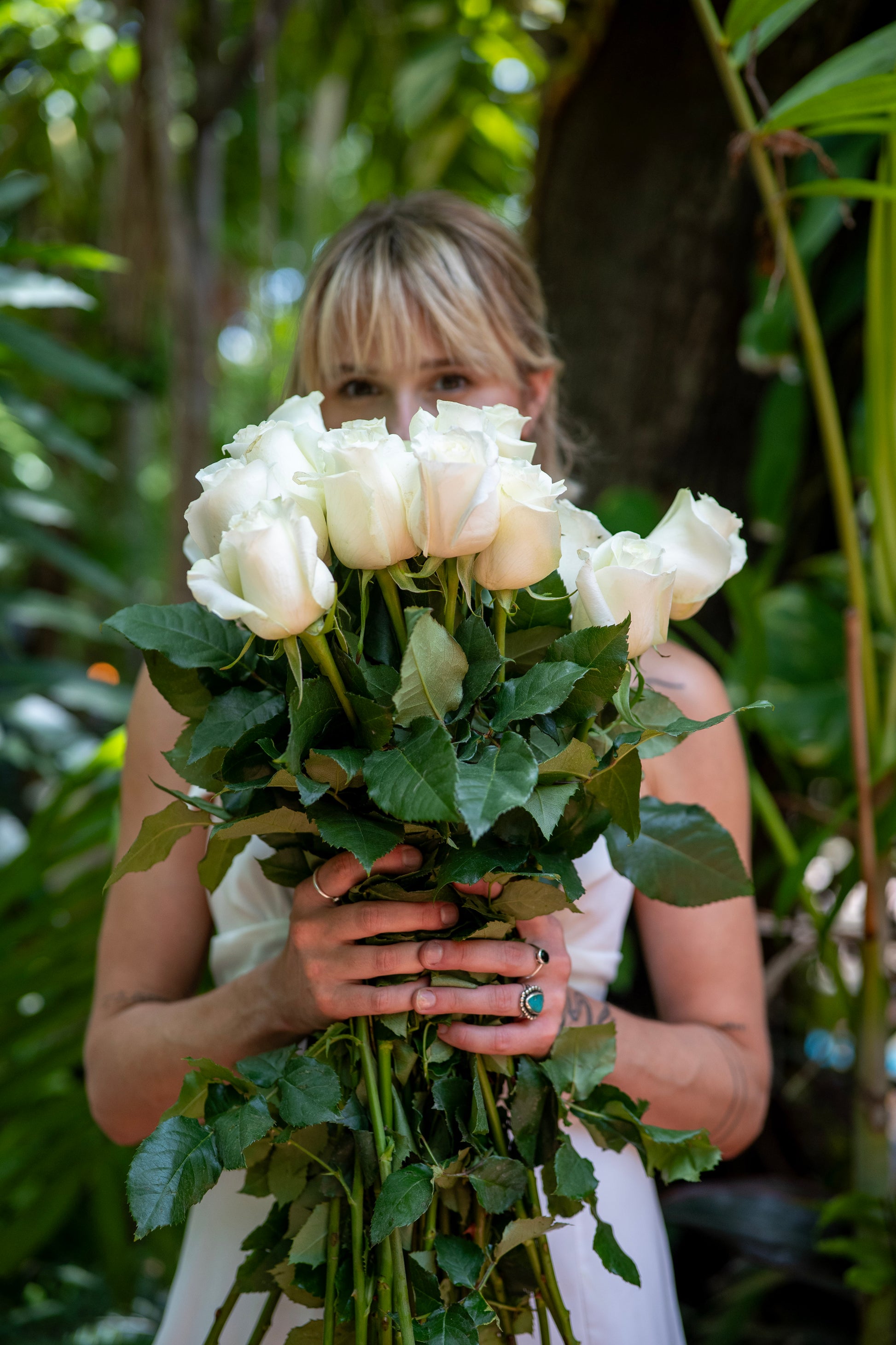Woman holding a bouquet of white roses in a natural setting
