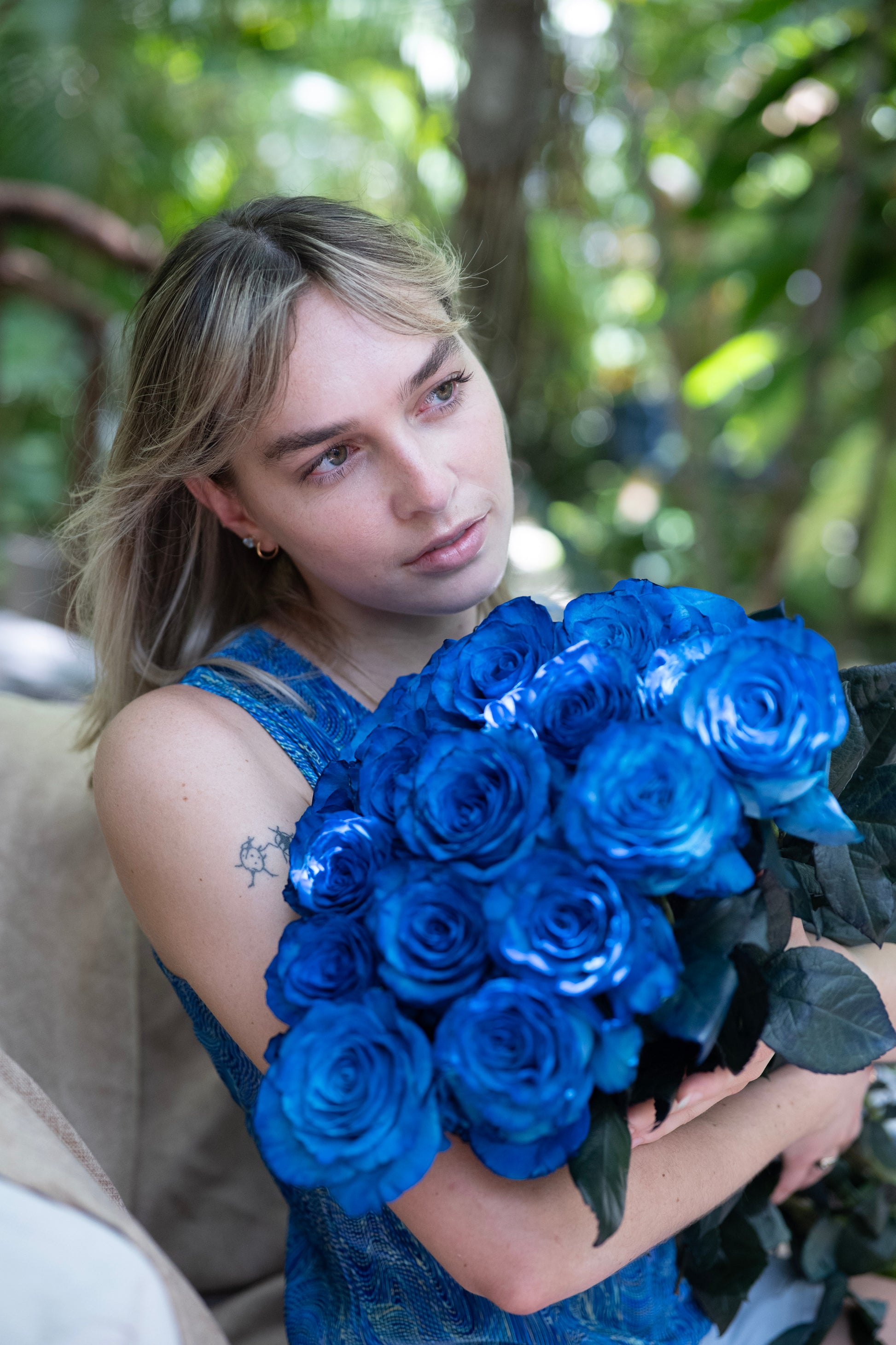 Woman holding a bouquet of blue roses with a blurred natural background