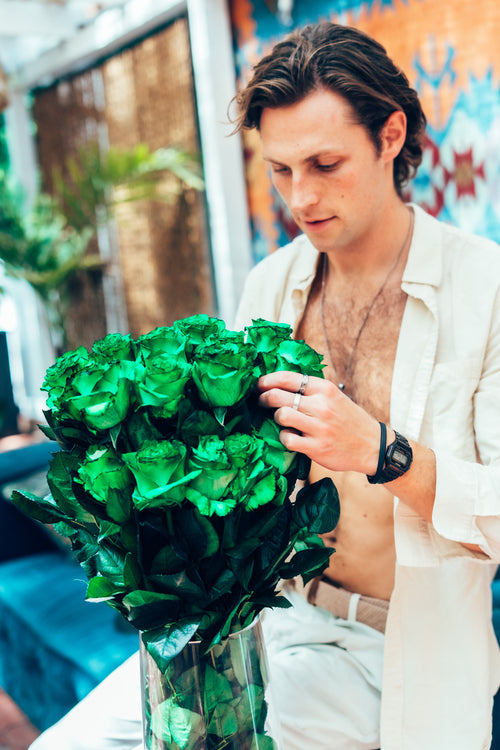 Man holding a large bouquet of green flowers outdoors