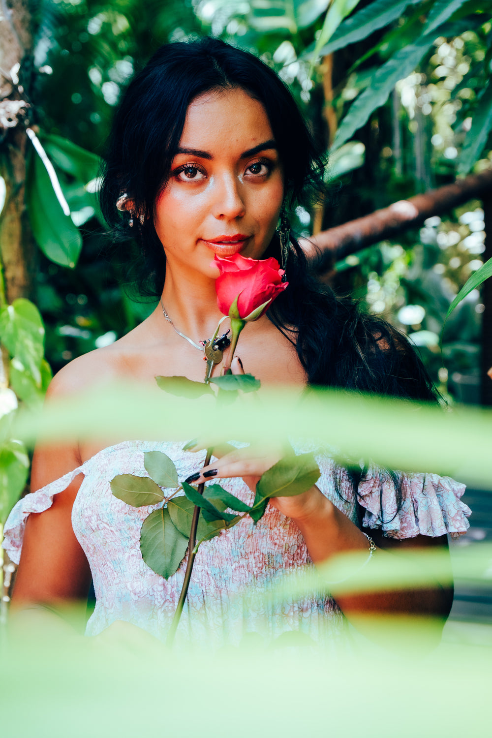 Woman holding a hot pink rose in a lush green garden