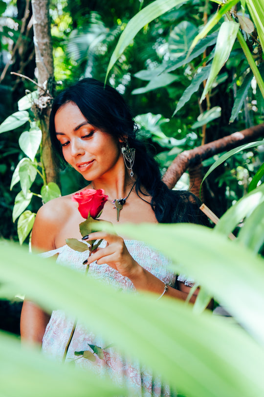 Woman holding a hot pink rose amidst green foliage