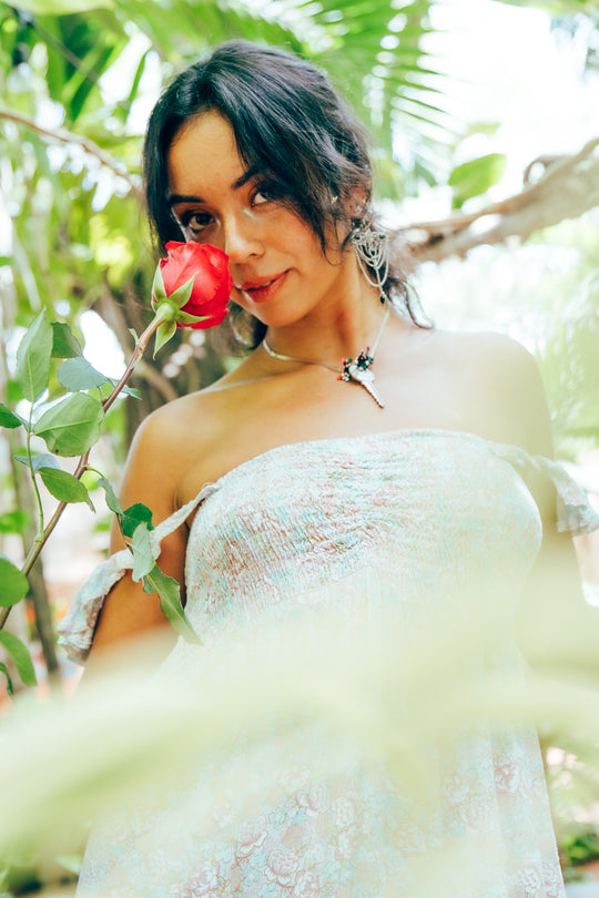 Woman holding a hot pink rose in a forest setting