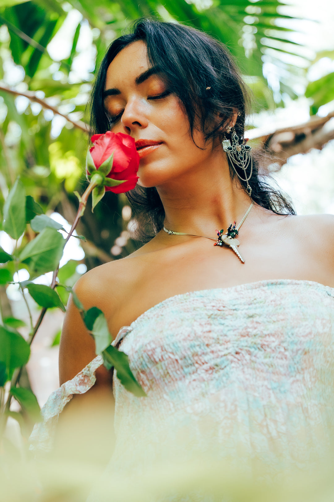 Woman holding a hot pink rose in a natural setting with greenery