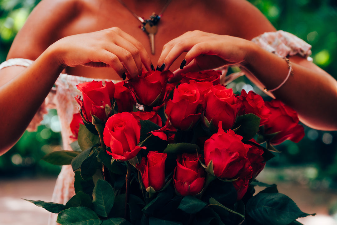 Person holding a bouquet of hot pink roses with a blurred green background