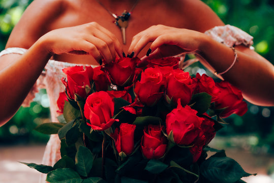 Person holding a bouquet of hot pink roses with a blurred green background