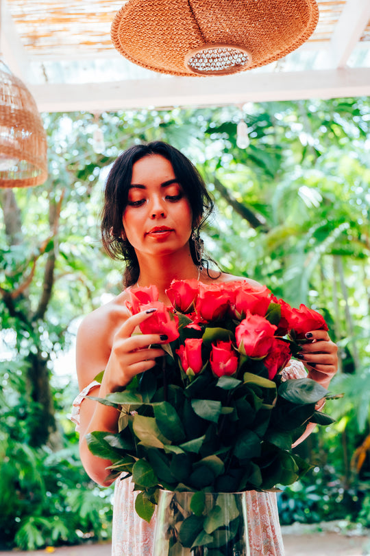 Woman holding a bouquet of hot pink roses in a tropical setting