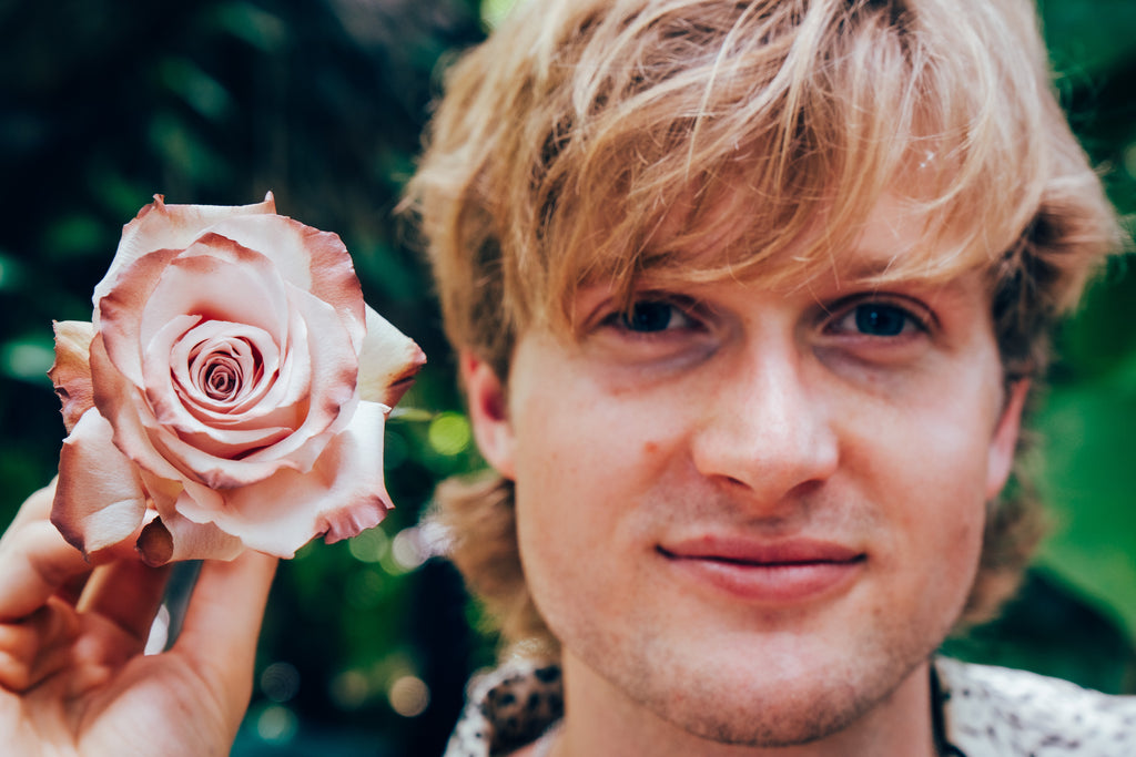 Person holding a pink rose with a blurred green background